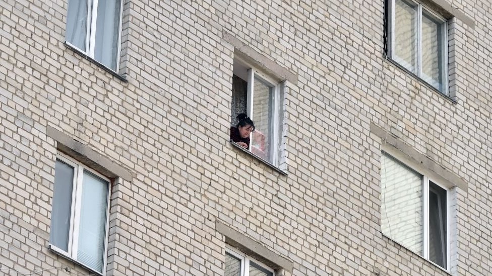 Woman at the window in a block of flats in Ukraine