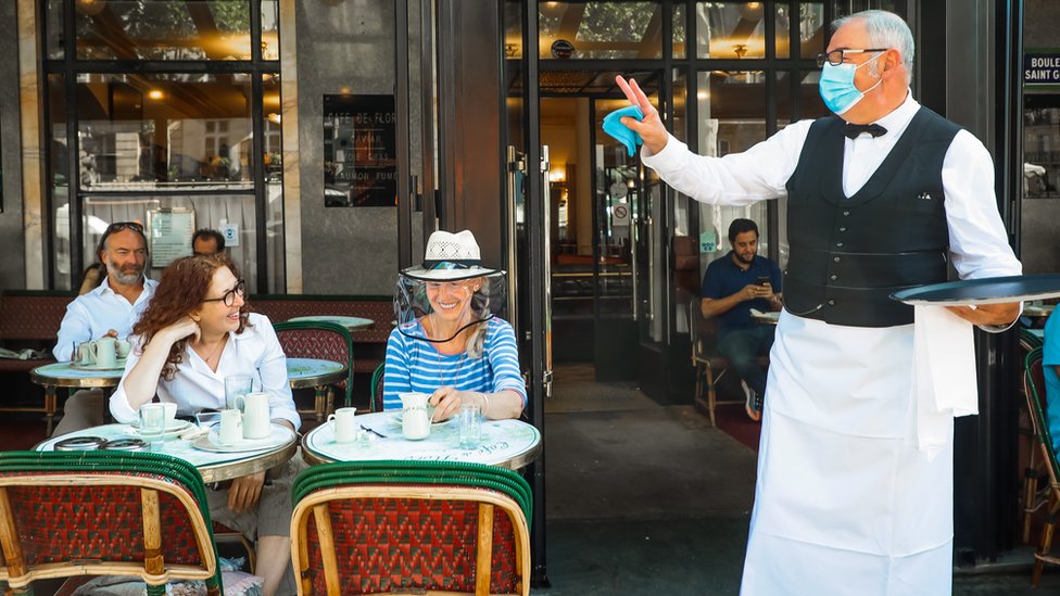 A waiter gestures towards customers in Paris
