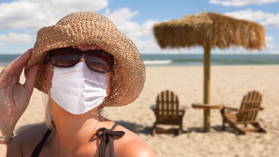 žena nosi masku na plaži