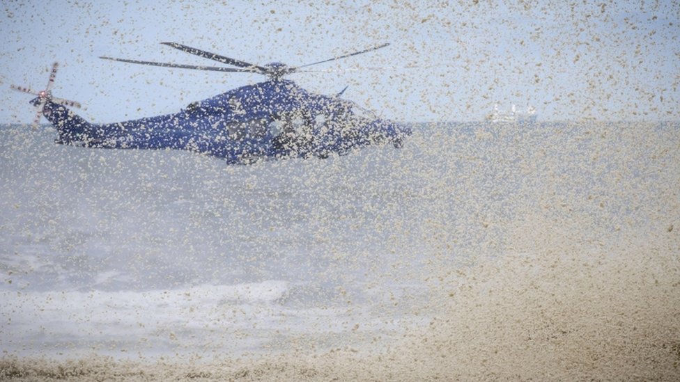 The downdraft from a police helicopter blows away surf from beachside rocks in Scheveningen, The Netherlands, on May 14, 2020