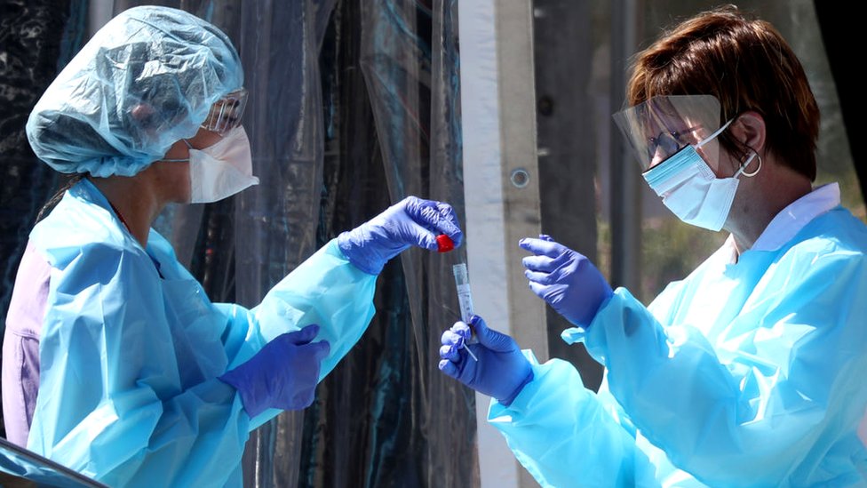 Korona virus: Moguće strože mere u Srbiji, počinje poslednja faza testiranja vakcine u Americi 1 Medical personnel secure a sample from a person at a drive-thru Coronavirus testing station in the US. 12 March 2020