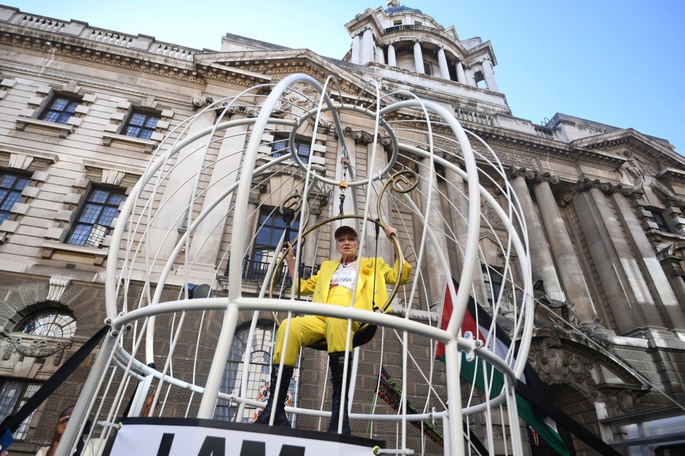 Dame Vivienne Westwood suspended in a large bird cage outside the Old Bailey in London