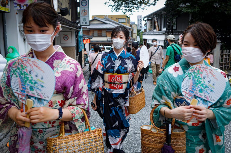 Women wearing protective face masks walk near Kiyomizudera temple in Kyoto, Japan.