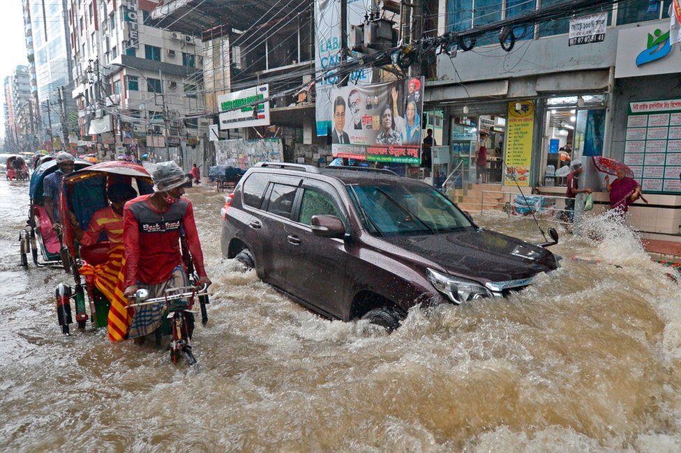 Commuters make their way through a water-logged street