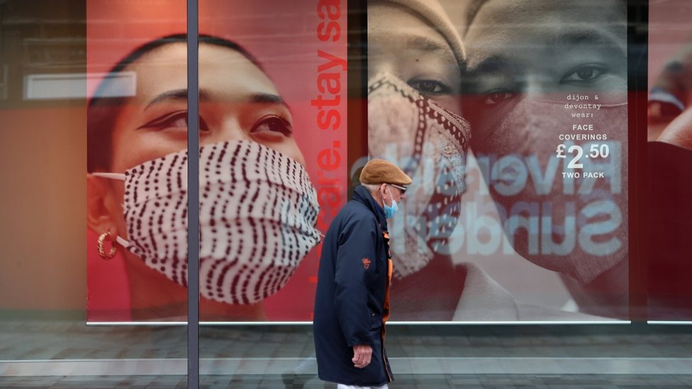 A man walks past an advertisement for face coverings in Sunderland