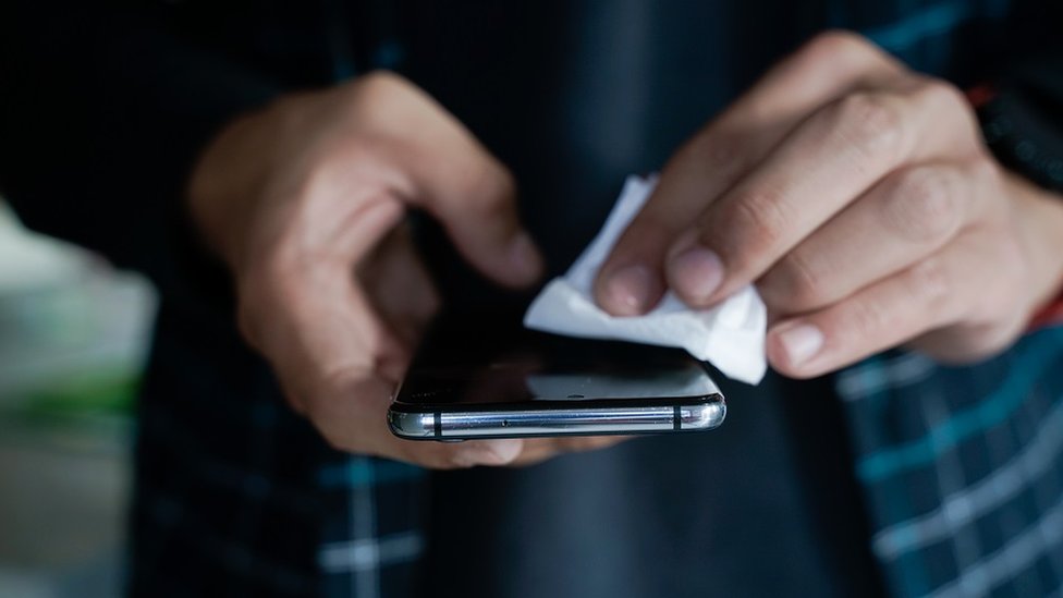 Korona virus: Kovid-19 „može da preživi na telefonu ili novcu do 28 dana" 1 wiping smartphone screen - stock photo
