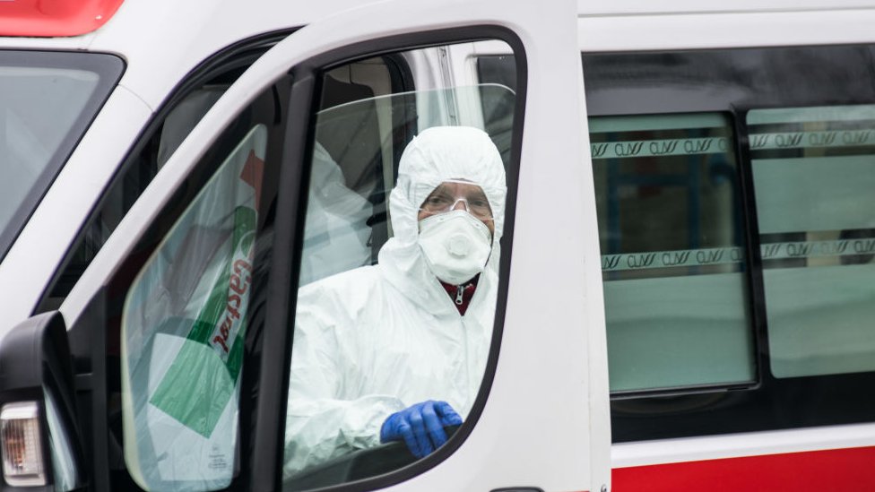Korona virus: Šta znači „spljoštiti krivu“ širenja i zašto je to ključno 3 A hospital worker wearing protective equipment stands next to an ambulance in Padova, Italy