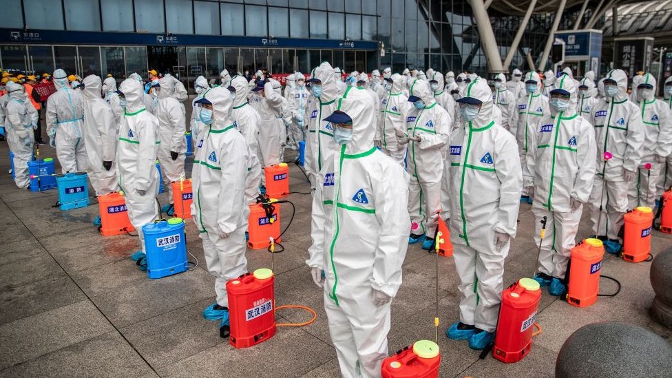 A squad of workers prepare to carry a disinfection operation at a Wuhan train station in March