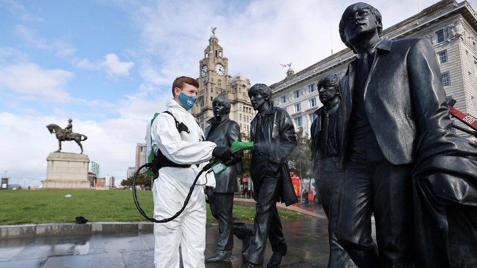 Korona virus: Lekari u Srbiji upozoravaju na rast broja zaraženih - u Francuskoj najviše preminulih od aprila 5 A man wearing a face covering cleaning statues of the Beatles