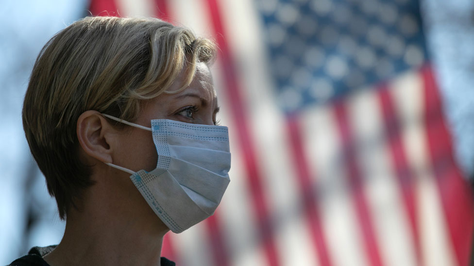 žena s maskom ispred američke zastave