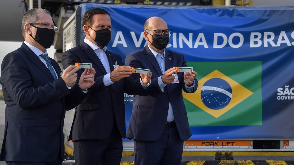 Sao Paulo Governor Joao Doria (C), Sao Paulo state Health Secretary Dr. Jean Gorinchteyn (L), and Butantan Institute Director Dimas Covas (R), pose for photos next to a container carrying doses of the CoronaVac vaccine at Guarulhos International Airport in Guarulhos, near Sao Paulo, Brazil, on December 03, 2020.