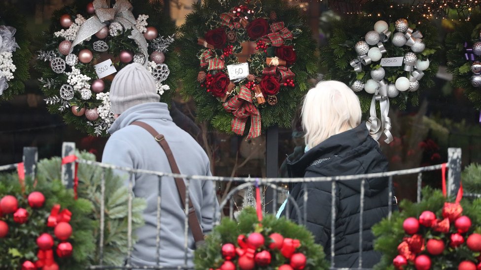 people looking at Christmas wreaths