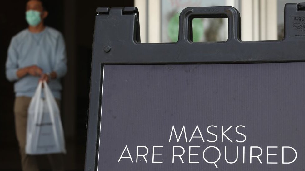 A sign tells store customers to wear masks to prevent the spread of Covid-19