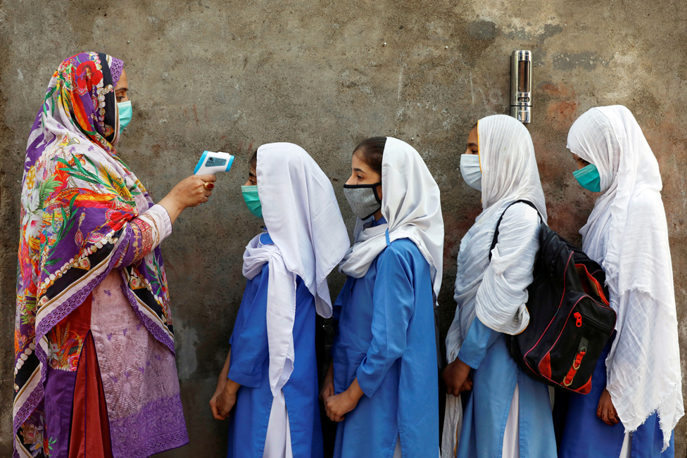 Students wear protective face masks as they have their temperature checked before entering a class in Peshawar, Pakistan 23 September 2020