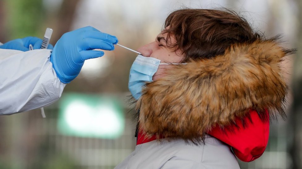 A healthcare worker collects a nasal swab sample of a boy at a drive in COVID-19 testing center in Brussels, Belgium, 12 January 2021