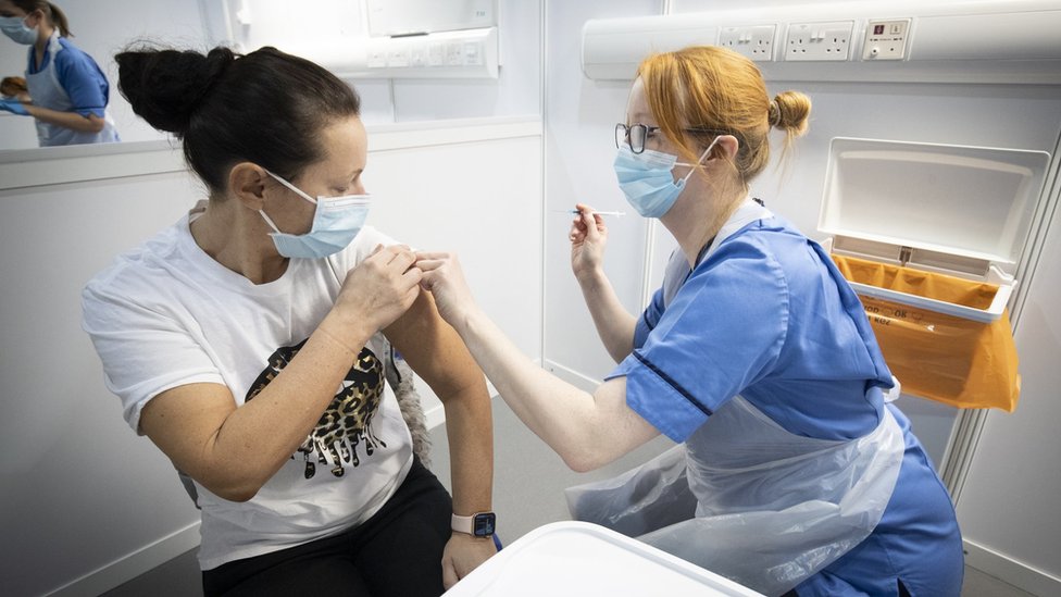 A nurse gives a woman a vaccine