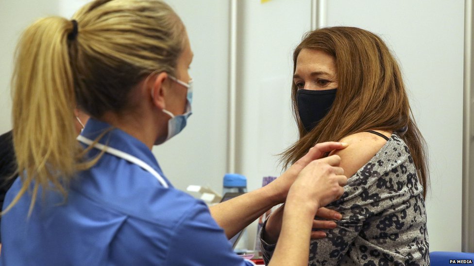 Caroline Nicolls receiving a Covid-19 vaccine, administered by nurse Amy Nash, at the Madejski Stadium in Reading