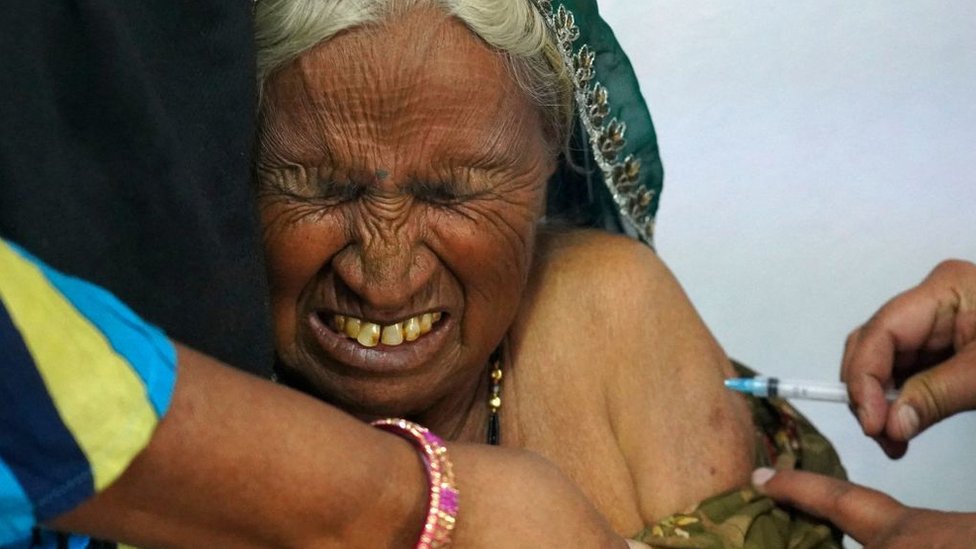 Korona virus i Indija: Zašto čitavom svetu treba da je stalo do zdravstvene krize u jednoj od najmnogoljudnijih zemalja 15 An elderly woman reacts as she is inoculated with the Covid-19 coronavirus vaccine at a government hospital on the outskirts of Ajmer