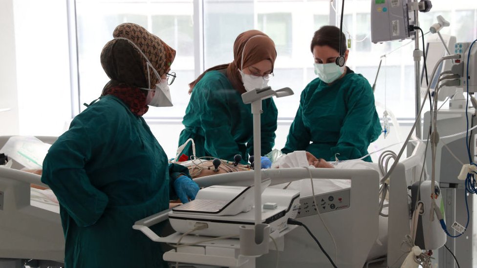 Three masked medical workers tend to a patient in an intensive care unit in Ankara