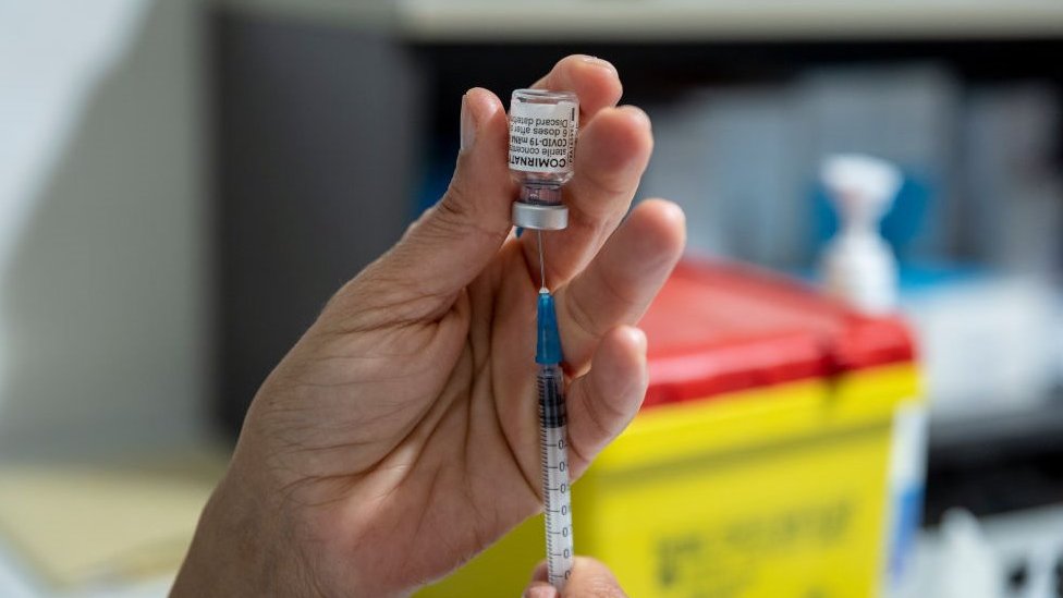 Some vaccine being drawn from a vial into a syringe
