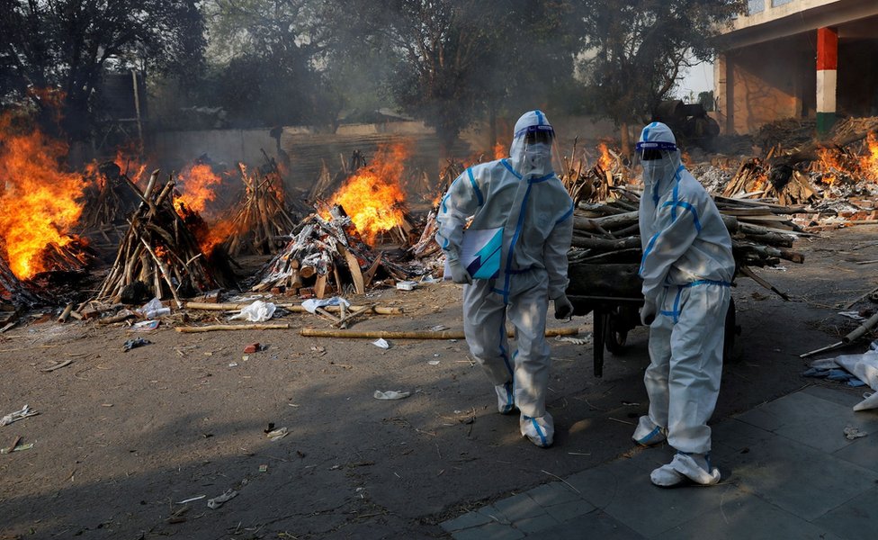 Health workers carry wood for funeral pyres in New Delhi, India