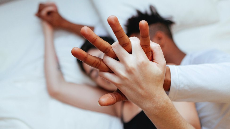 Korona virus, seks i psihologija: Kako je pandemija promenila seksualni život 2 A couple cuddling in bed, holding raised hands