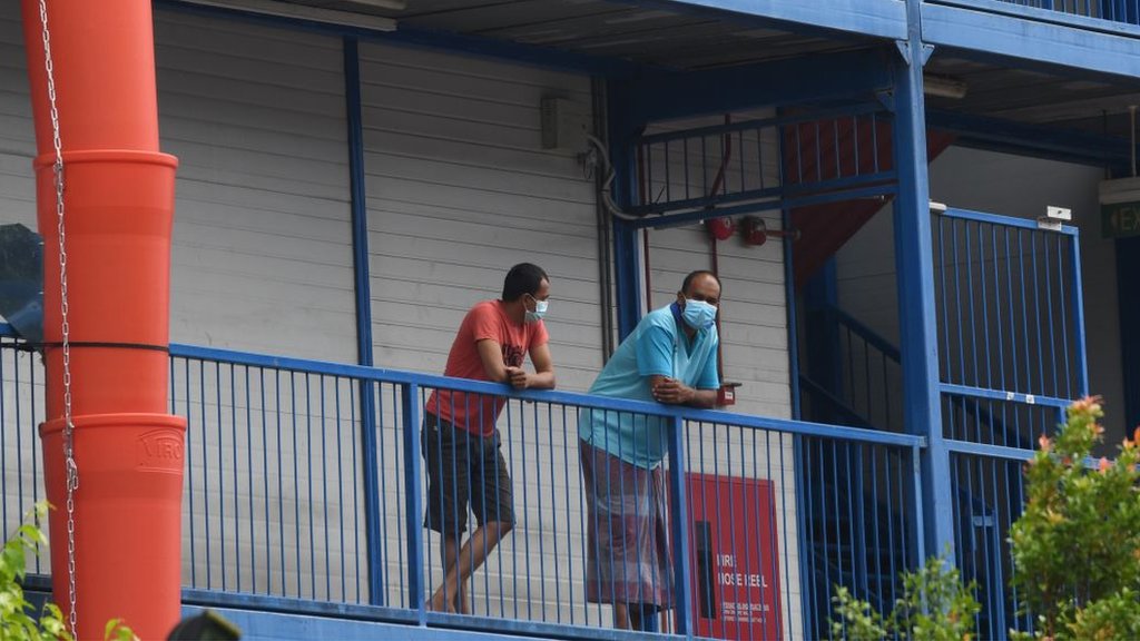 Korona virus i Singapur: Kako je na najboljem mestu za život tokom pandemije 6 Migrant workers wearing face masks as prevention for the spread of the COVID-19 coronavirus look out from a quarantined dormitory building in Singapore on 20 May 2020.