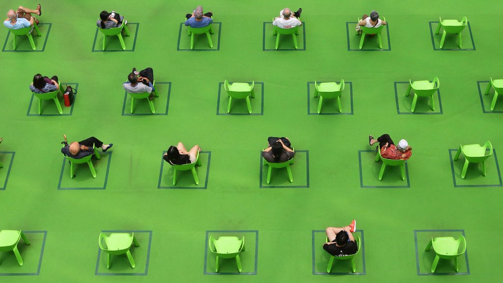 Korona virus i Singapur: Kako je na najboljem mestu za život tokom pandemije 5 People sit on chairs marked out to maintain social distancing amid the COVID-19 pandemic on 19 March 2021 in Singapore