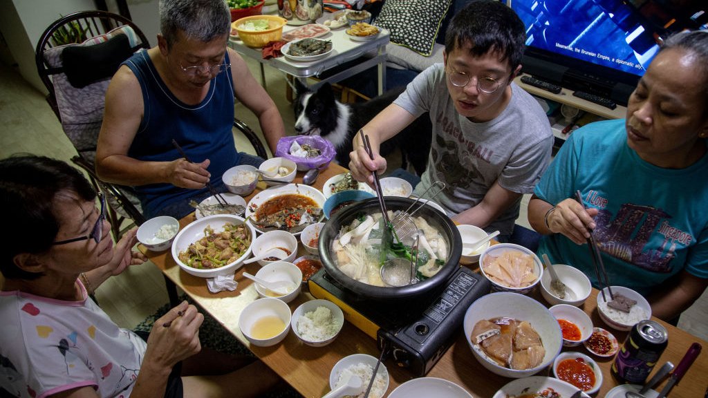 Korona virus i Singapur: Kako je na najboljem mestu za život tokom pandemije 3 A family partakes in a steamboat meal for their reunion dinner at home on the eve of the lunar new year on 11 February 2021 in Singapore.