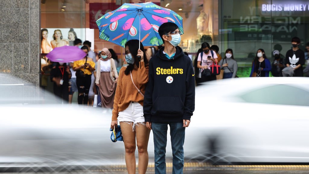 Korona virus i Singapur: Kako je na najboljem mestu za život tokom pandemije 1 A couple wearing protective masks wait to cross a street in the rain on 10 January 2021 in Singapore