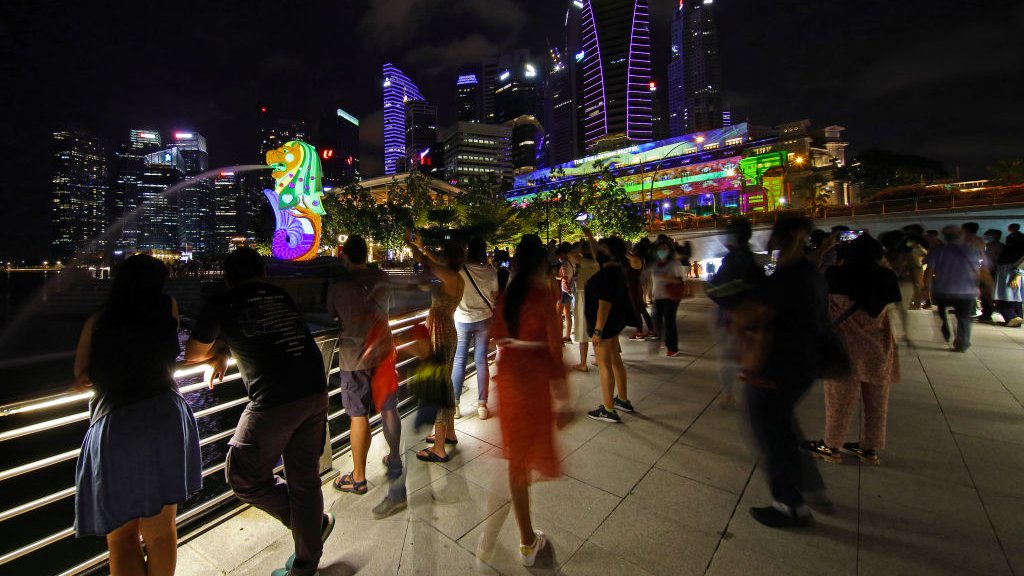 Korona virus i Singapur: Kako je na najboljem mestu za život tokom pandemije 8 People watch light projection with illuminated artworks on the facade of the Merlion and the Fullerton Hotel at Marina Bay on 30 December 2020 in Singapore.