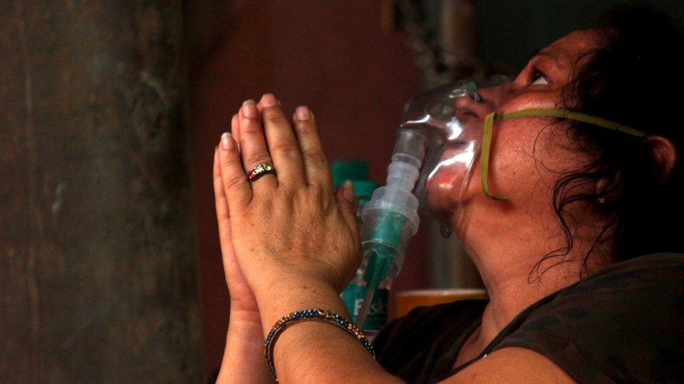 Korona virus: U Srbiji sve više mladih koji se vakcinišu, novi crni rekord u Indiji 5 A woman with an oxygen mask on prays