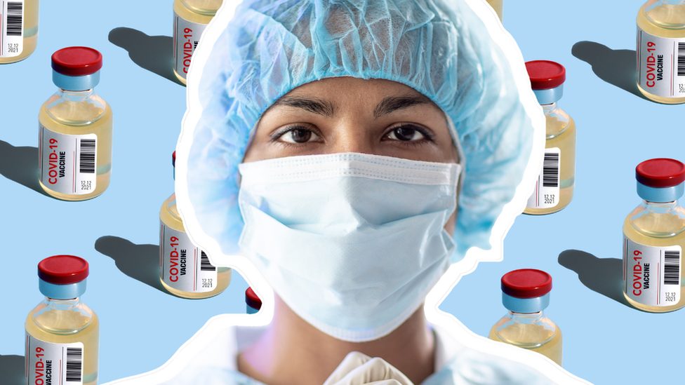 Someone in a mask in front of a pattern of vials
