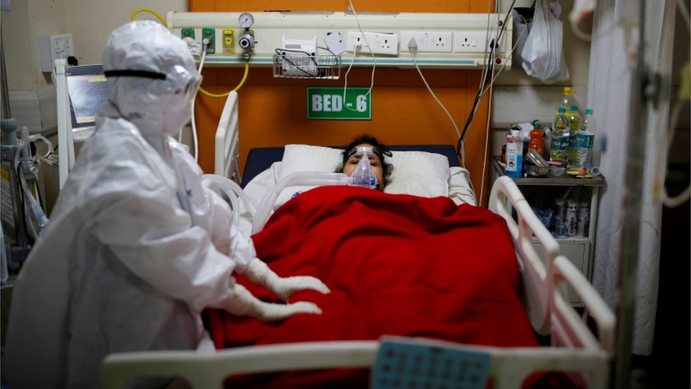 Woman in hospital bed with doctor in PPE