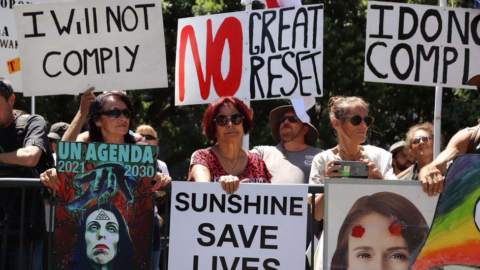 Korona virus, klimatske promene i teorije zavere: Šta je „Veliki reset“ i zašto neki veruju da se svetom upravlja iz jednog centra moći 2 People hold placards protesting the United Nations and the "great reset" at a rally of conspiracy theorists and supporters of US President Donald Trump on January 14, 2021 in Wellington, New Zealand