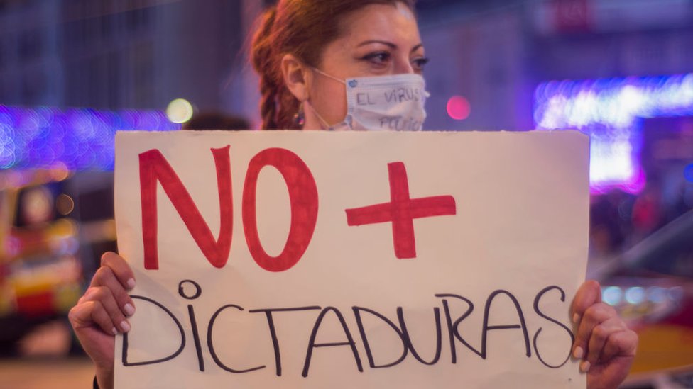 Woman in Madrid protesting with sign reading "No to dictatorship"