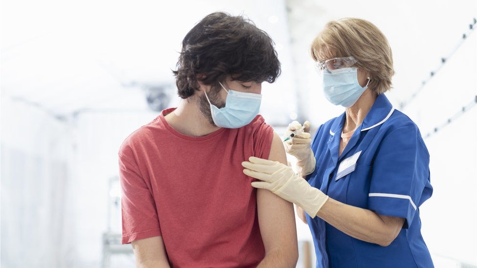 Korona virus: U Srbiju stigle supstance za proizvodnju Sinofarm vakcine, antivakseri upali u zgradu TV Slovenija 1 young man being vaccinated