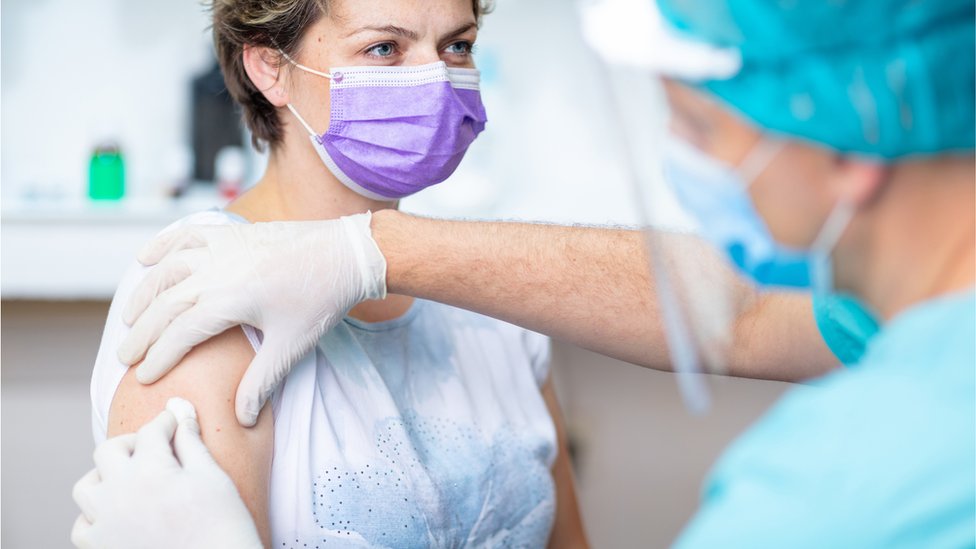 Korona virus: Polemika oko mera u Srbiji, britanski stručnjaci pozivaju na vakcinaciju protiv sezonskog gripa 1 Nurse in protective gear giving patient a vaccination