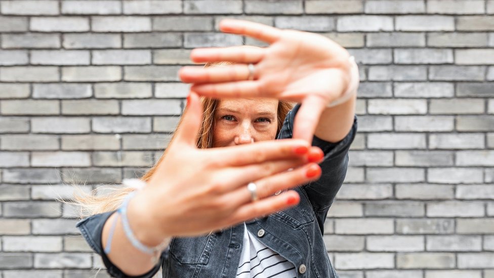 Korona virus i mentalno zdravlje: Saveti kako pobediti anksioznost posle zatvaranja 5 Close-up of woman against grey brick wall making finger frame sign