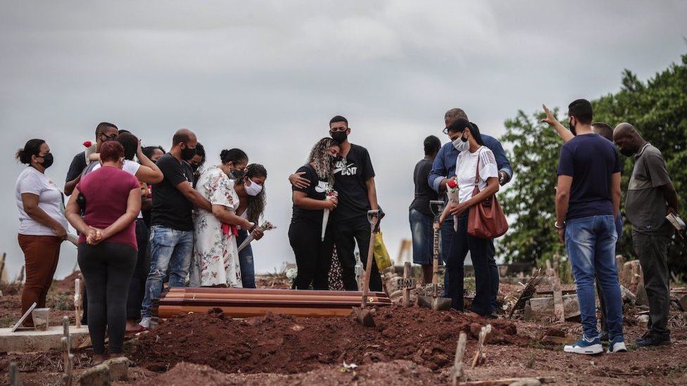 Relatives mourn the death by Covid-19 of a loved one during his burial, in a cemetery in the north of Rio de Janeiro, Brazil, 13 April 2021