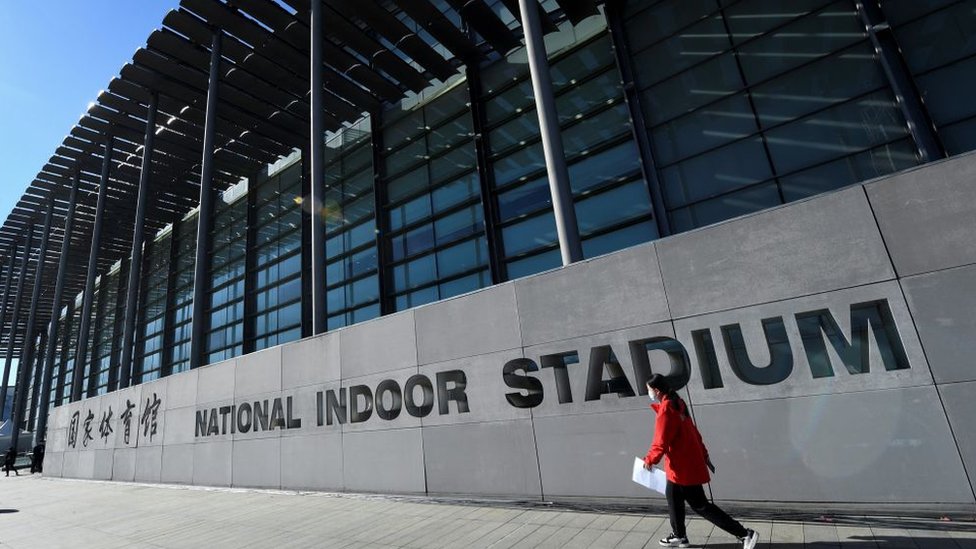 Korona virus i Kina: Zašto se vlasti i dalje trude da održe broj slučajeva kovida na nuli 3 A woman walks past the National Indoor Stadium before an ice hockey match, part of a 2022 Beijing Winter Olympic Games test event, in Beijing on November 10, 2021.