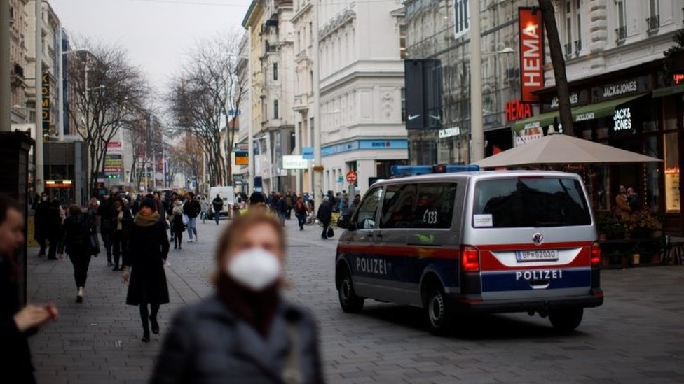Korona virus i Austrija: Kako dijaspora živi pod novim merama - „Beč je podeljen grad na vakcinisane i nevakcinisane" 4 A police car is seen as pedestrians walk along a shopping street after the Austrian government placed roughly two million people who are not fully vaccinated against the coronavirus disease (COVID-19) in lockdown