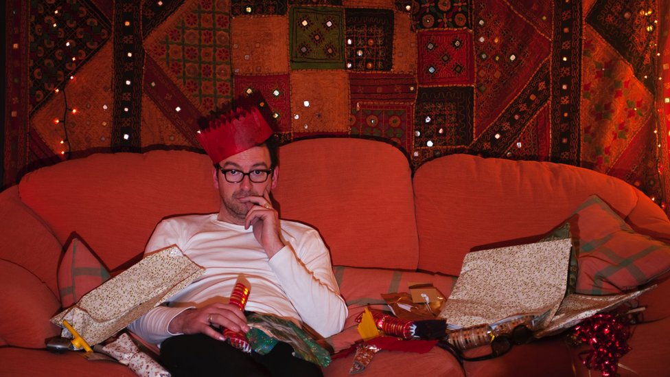 Doček Nove godine, Srbija i region: Od koncerata, preko performansa i zabrana, do lutrije - koliko će koštati novogodišnja noć 6 Man on couch wearing Christmas hat