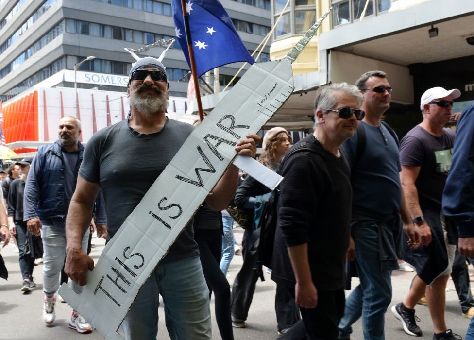 Korona virus: Obavezna vakcinacija - tri razloga za i protiv 2 'This is a war': A protester holds up a needle sign in Melbourne, Australia