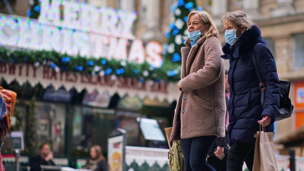Korona virus: U Srbiji manje od 1.000 novozaraženih, u Danskoj zbog rekordnog broja zaraženih pooštravaju mere 1 Two women wearing masks walk in Cardiff in front of a Merry Christmas sign
