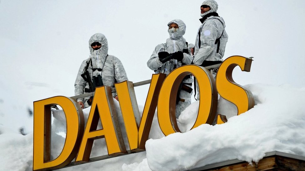 Korona virus: Omikron otkazao Svetski ekonomski forum u Davosu, Holandija zaključana, u Londonu vanredna situacija 2 Armed security personnel stand guard on the rooftop of a hotel, next to letters reading "Davos"