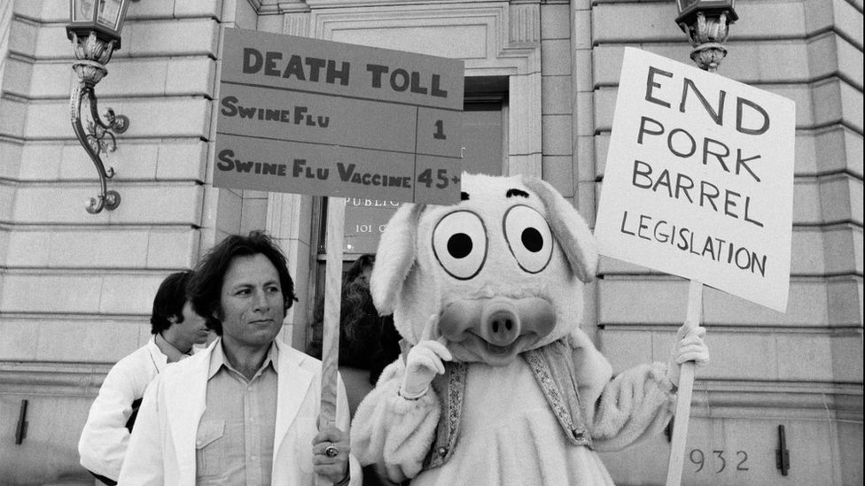 Korona virus i vakcina: Kako su antivakcinaši vršili uticaj na svet kroz istoriju 29 Protesters wearing white coats stand next to a protester in a pig costume, holding a sign saying: "Death toll; swine flu: 1; Swine flu vaccine: 45+" and another saying: "End pork barrel legislation".