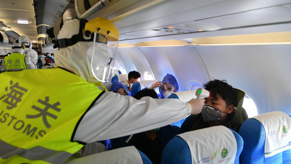 Zimske olimpijske igre: Kako izgleda kineska kovid politika i da li radi 3 A customs officer conducts temperature check onboard after a flight landed in China
