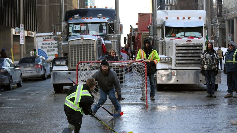 Protesters play street hockey as trucks block a street in downtown Ottawa