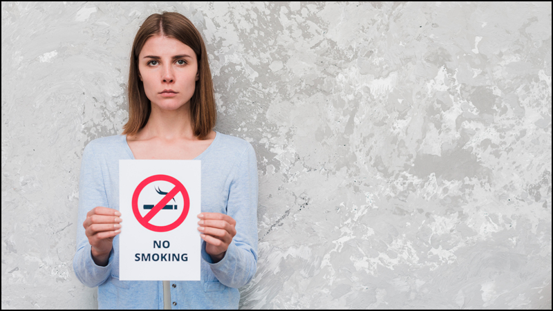 Da li znate koja će to država biti prva na svetu bez duvanskog dima? 2 serious woman holding with no smoking text sign standing against weathered wall